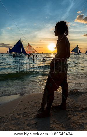 BORACAY, WESTERN VISAYAS, PHILIPPINES - MARCH 24, 2017: Native man with his surfboard waiting the best wave to go the sea.