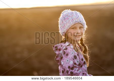 outdoor portrait of young happy smiling child girl in knitted hat on outdoor natural background 