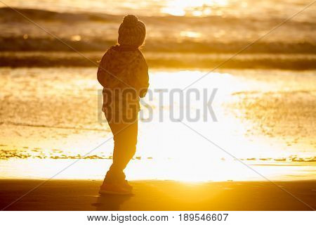 outdoor portrait of young happy smiling child girl in knitted hat on outdoor natural background