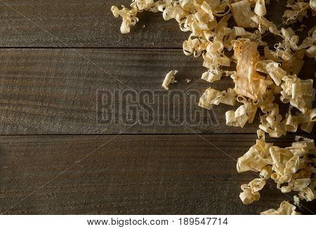 Light brown wood shavings from carpenter's hand planer or chisel work on wooden boards background with copy space