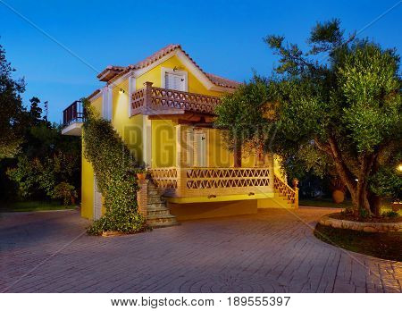 ZAKYNTHOS ISLAND, GREECE, MAY,30, 2016: Evening view on yellow classic Greek villa house cottage terrace Porto Gerakas villa in olive trees garden for tourists Evening highlighting. Holidays vacations