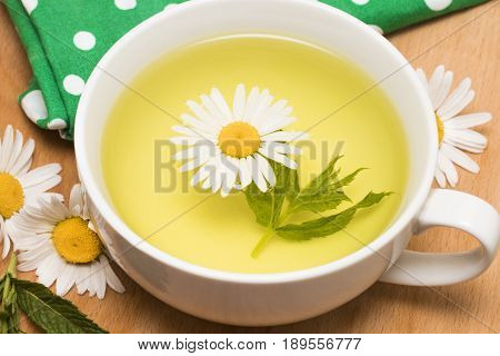 Cup Of Herbal Tea With Chamomile Flowers On A Wooden Table