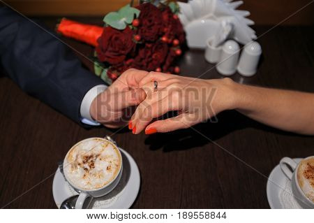 Bride And Groom Holding Each Other's Hands While Sitting At The Table