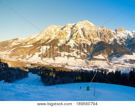 Downhill slope in Saalbach Hinterglemm Leogang winter resort, Tirol, Austria, Europe. Sunny morning with clear sky and illuminated mountain massive on the background.
