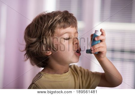 Boy using asthma inhaler to treat inflammatory disease wheezing coughing chest tightness and shortness of breath. Allergy treating concept.