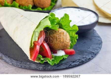 Chickpea falafel balls with vegetables and white sauce roll sandwich preparation horizontal copy space