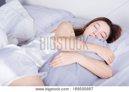 Woman Sleeping With Bolster Pillow On Bed In Bedroom