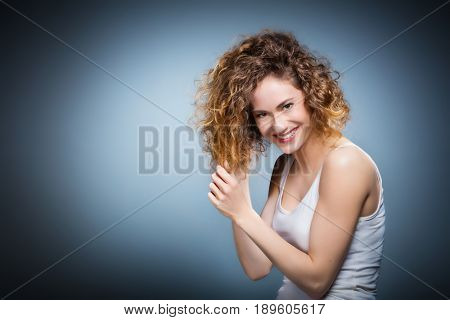 Geniue portrait of a young positive, smiling girl softly touching her hair. Natural, healthy and authentic woman. Freedom concept.
