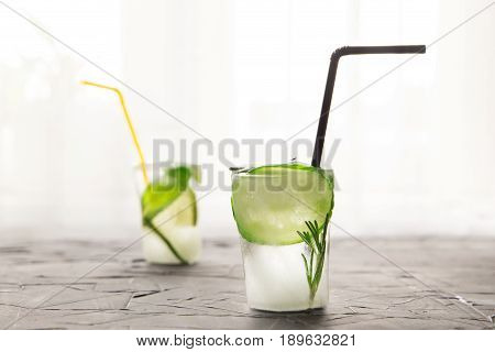 two glasses with fresh cocktail made of ice on concrete table in front of window. concept