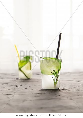 two glasses with fresh cocktail made of ice on concrete table in front of window. concept. vertical