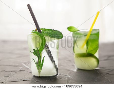 two glasses with fresh cocktail made of ice on concrete table in front of window. concept