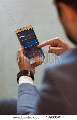 Close up of a businessman using smart phone. Focus on mobile device.