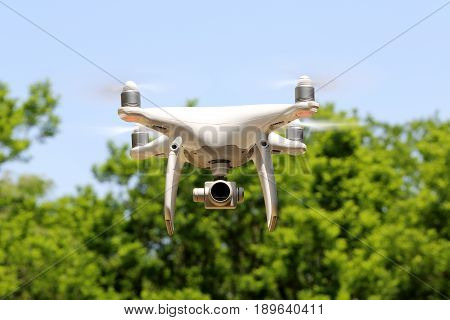 KAGAWA, JAPAN - MAY 20, 2017: White remote controlled Drone Dji Phantom4 Pro equipped with high resolution video camera flying in air and blue sky in the forest