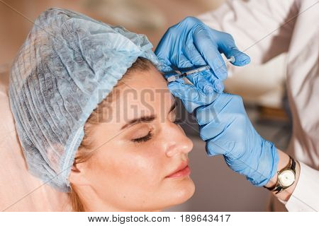 Woman gets injection in her face. Beauty woman giving injections. Young woman gets beauty facial injections in the cosmetology salon. Face aging injection. Aesthetic Medicine, Cosmetology.