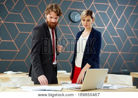 Two newsreaders standing by workplace and discussing notes