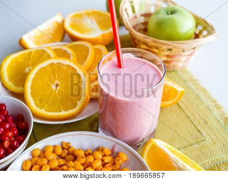 Vitamin smoothies from berries and fruits on a table among oranges