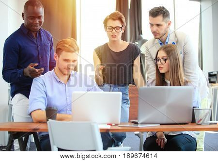 Teamwork concept.Young creative coworkers working with new startup project in modern office.Group of people analyze data on desktop computer.