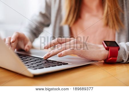 Casual hi-tech. Intelligent charming young lady using her gadget for fulfilling her assignment while preparing a draft of her study for professor