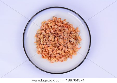 Dried shrimp on a white ceramic plate with blue outer ring line.  White background.
