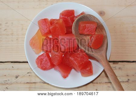 Squared papaye on a white plate with a wooden spoon