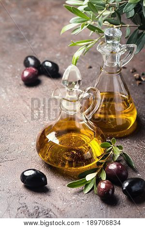Olive oil in a glass bottle and olive branch on brown stone table