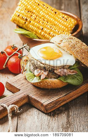 Homemmade Bacon Hamburger with fried Egg, Lettuce and lentil burger with a garnish of corn and tomatoes