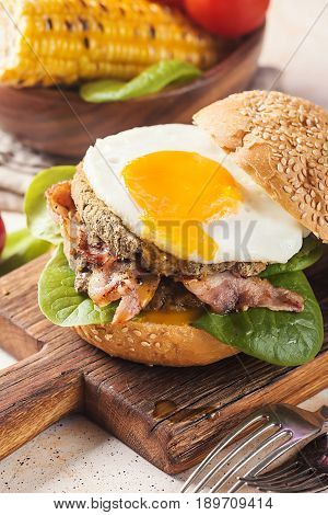 Homemmade Bacon Hamburger with fried Egg, Lettuce and lentil burger with a garnish of corn and tomatoes