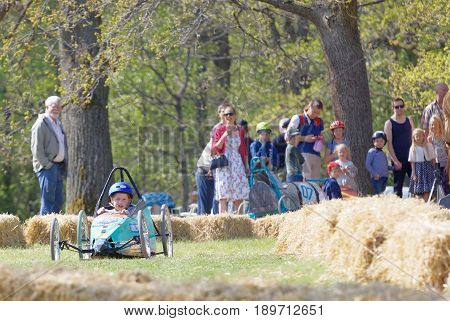 STOCKHOLM SWEDEN - MAY 21 2017: Concentrated little girl driving a home made soapbox car downhill on a field in the race Gardesloppet at Djurgarden Stockholm Sweden. May 21 2017