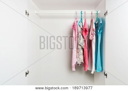 Clothes Hanging On Rail In White Wardrobe.