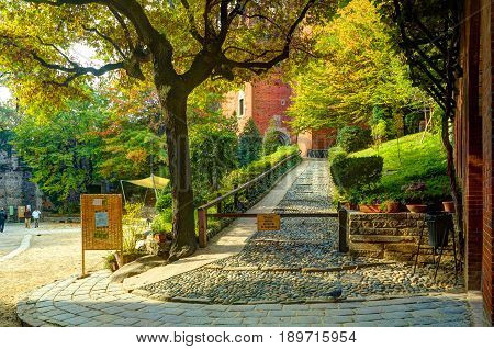TURIN, ITALY, OCT, 20, 2007: Evening view on green trees antique castle patio Borgo Medioevale city garden park. Highlighting sun. Italy Italian architecture ornaments. Italy holidays vacations tours