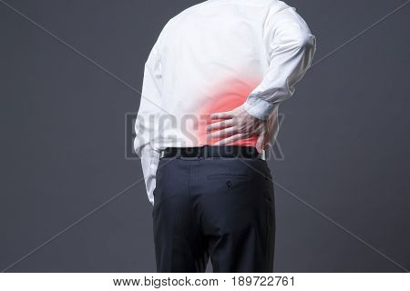 Back pain kidney inflammation ache in man's body on gray background with red dot