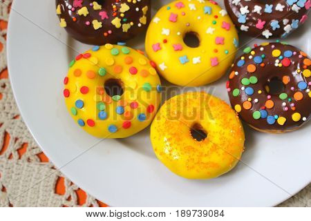Yellow and brown donuts on a white plate