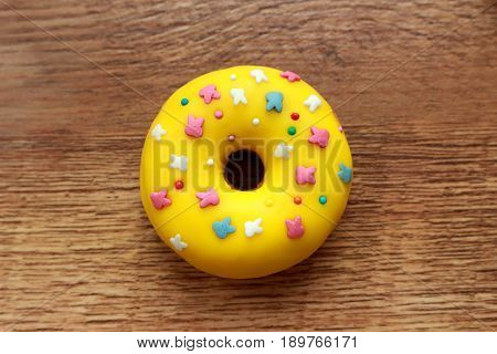 Single yellow donut on a wood background