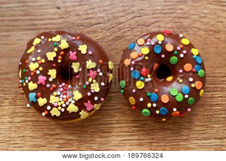 Two brown donuts on a wood background