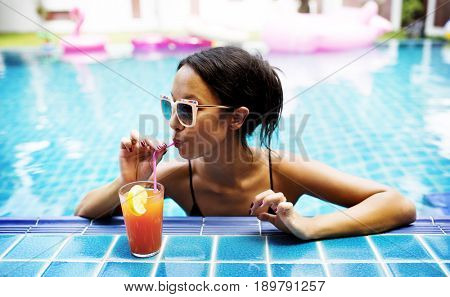 Asian woman drinking juice by the poolside