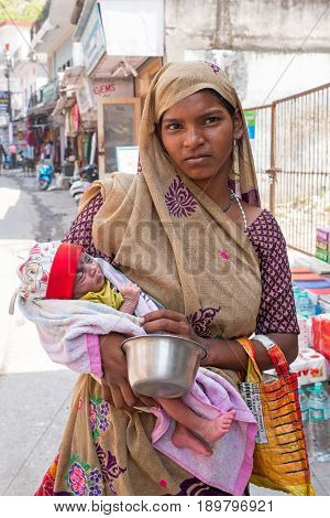 LAXMAN JHULA, INDIA - APRIL 15, 2017: Indian woman with newborn baby in the streets of Laxman Jhula in India