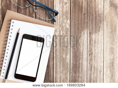 Top view office desk with smart phoneglassespencil and notebook on wooden table with copy space