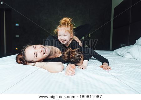 Mom and two daughters have fun on the bed in the bedroom