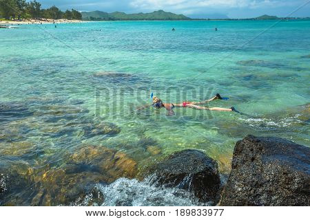 Woman snorkelling over coral reef in kailua beach, east shore in Oahu island, Hawaii, USA. Female bikini snorkeler swims in tropical sea. Watersport activity in Hawaii. Tropical destination holidays.
