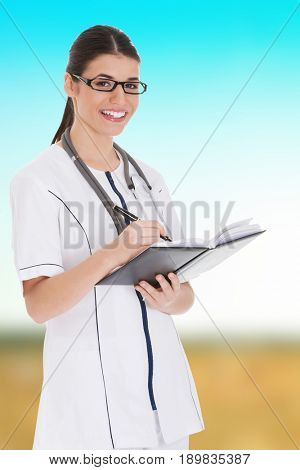 Young female doctor wirting in a book.