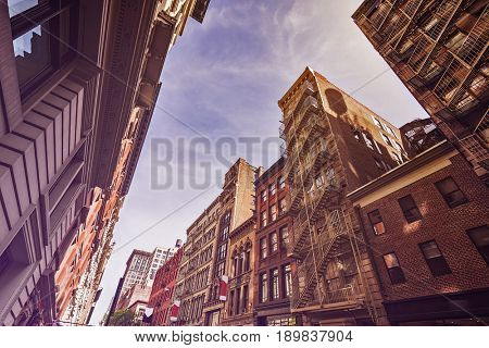 Narrow alley with Old apartment buildings and fire escapes on a sunny day in Midtown Manhattan, New York City