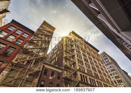 Narrow alley with Old apartment buildings and fire escapes on a sunny day in Midtown Manhattan, New York City