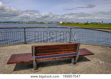 View of Cardiff Bay from the Barage with bench and railing in the foreground.
