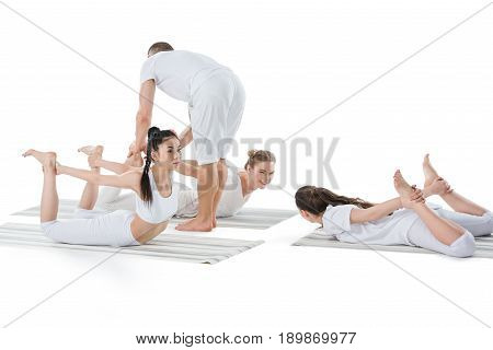 Multiethnic Girls Doing Frog Pose (bhekasana) With Instructor Isolated On White
