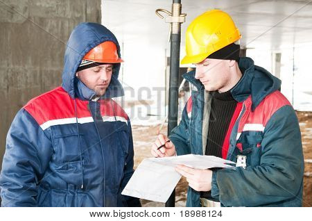 两名工程师与蓝图建筑工地建设者