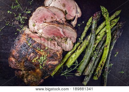 Barbecue Lamb Roast with green Asparagus as close-up on an old metal sheet 