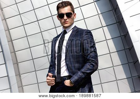 fashionable young man dressed in the gray background beautiful urban architectural form