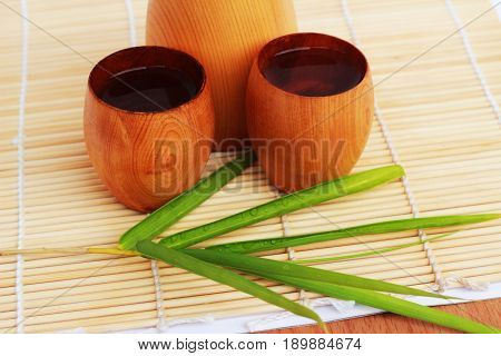 SAKE liqueur in a brown wooden bottle on a light brown background.