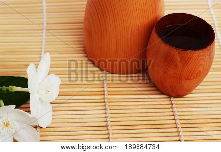 SAKE liqueur in a brown wooden bottle on a light brown background.