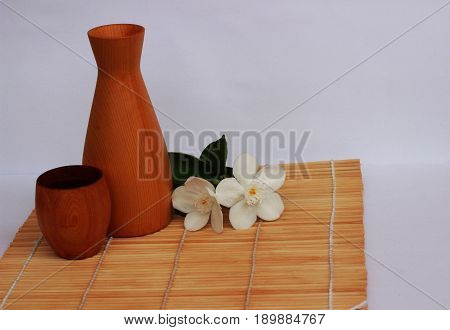 SAKE liqueur in a brown wooden bottle on a light brown background.